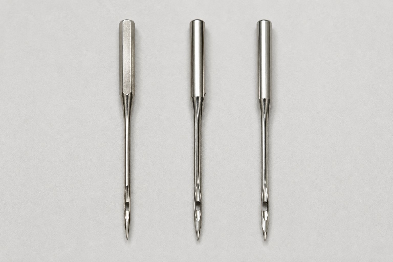 Household and industrial-style sewing machine needles arranged side by side.